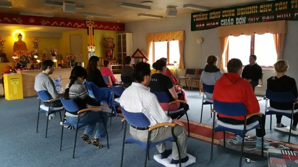 People meditating together in a hall with an altar in the background
